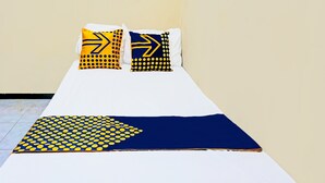 A bed with two pillows, one with a yellow and black arrow pattern and the other with a blue and yellow arrow pattern. - OYO Life  92091 Citra Omah Syariah (Malang)