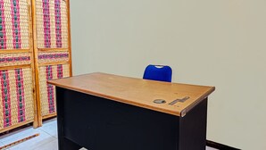 A classroom with a wooden desk, a blue chair, and a woven partition. - OYO Life  92091 Citra Omah Syariah (Malang)