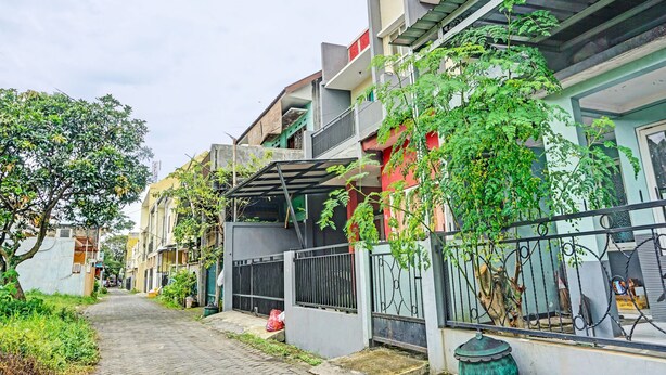 A narrow street lined with residential buildings, some with balconies and greenery. - OYO Life  92091 Citra Omah Syariah (Malang)
