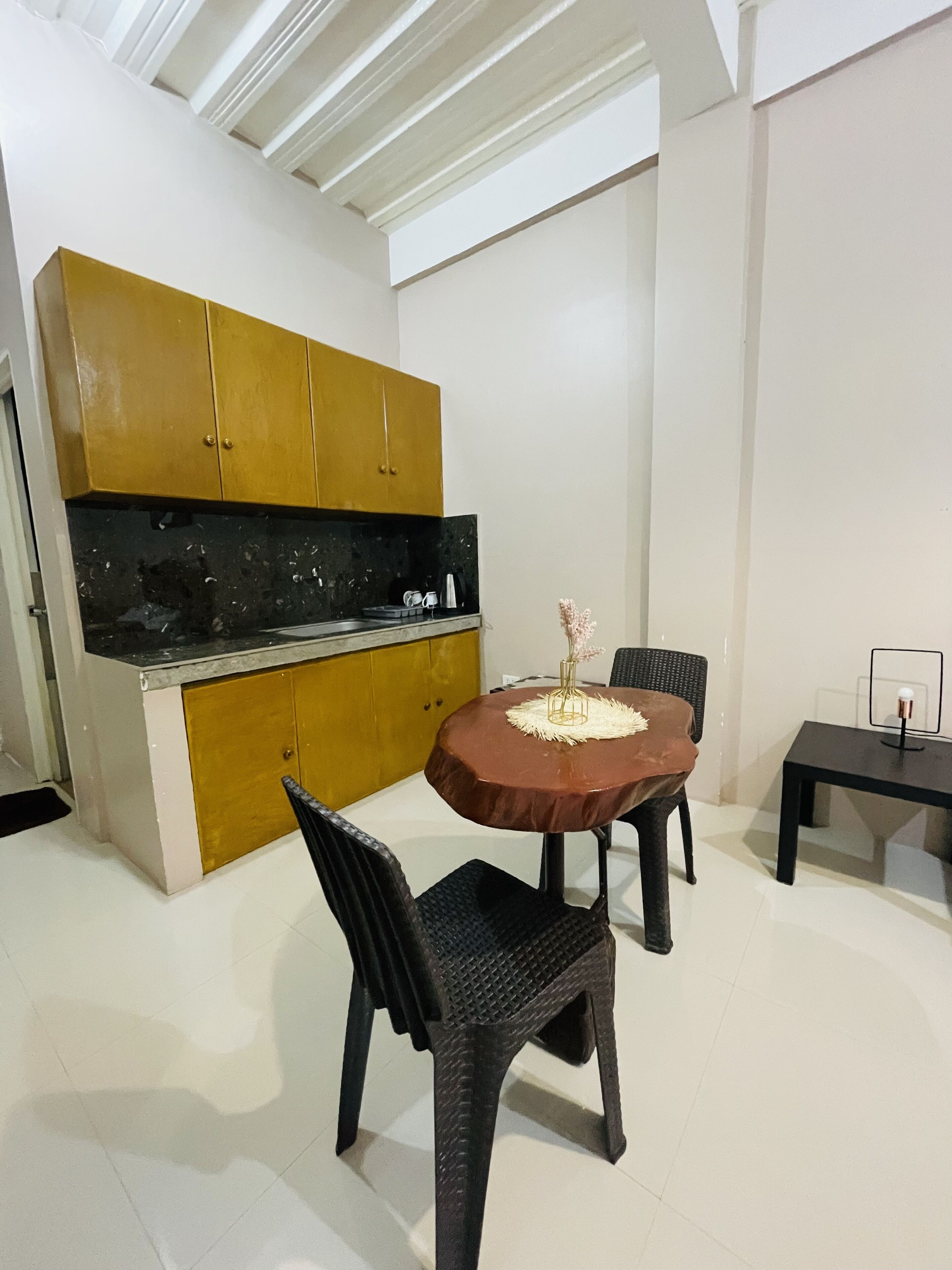 A modern kitchen with a black countertop, yellow cabinets, and a round dining table with chairs.