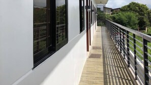A covered corridor with large windows, a wooden floor, and a railing. - Sto. Nino Residences (Lucena)
