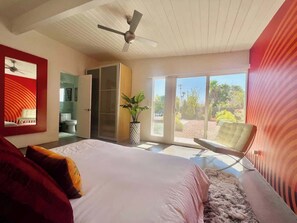 A bedroom with a bed, a ceiling fan, a sliding glass door to a balcony, and a chair. - Jazzy Mid-Century Designer with Speakeasy (Palm Springs)