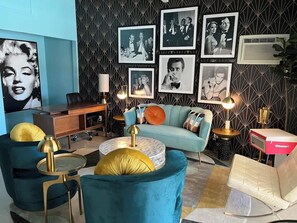 A modern living room with a blue sofa, matching armchairs, a round coffee table, and a desk with a lamp. - Jazzy Mid-Century Designer with Speakeasy (Palm Springs)