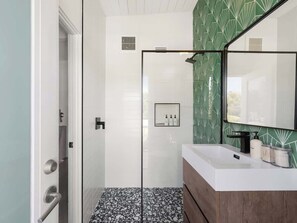 A bathroom with a shower, a vanity with a mirror, and a tiled floor. - Jazzy Mid-Century Designer with Speakeasy (Palm Springs)