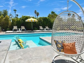 A pool area with lounge chairs, a hanging chair, and a yellow umbrella. - Jazzy Mid-Century Designer with Speakeasy (Palm Springs)