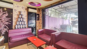 A room with purple sofas, a red table, and a wall with cans of Pro. - Hotel O Superstar Kost Dan Homestay (Tomohon)