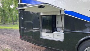 A mobile kitchen with a sink and storage drawers, a door, and a window.