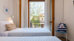 A bedroom with two beds, a balcony, and a chair with a bag. - Nida 18 in Cattolica (Cattolica)