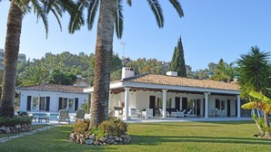 Une villa dotée d’un patio couvert, d’une piscine et d’une pelouse bien entretenue.
