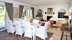 Un vaste salon comprenant un coin repas, une cheminée et un bar.