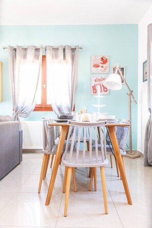 A dining area with a table, chairs, a lamp, and a window with curtains.