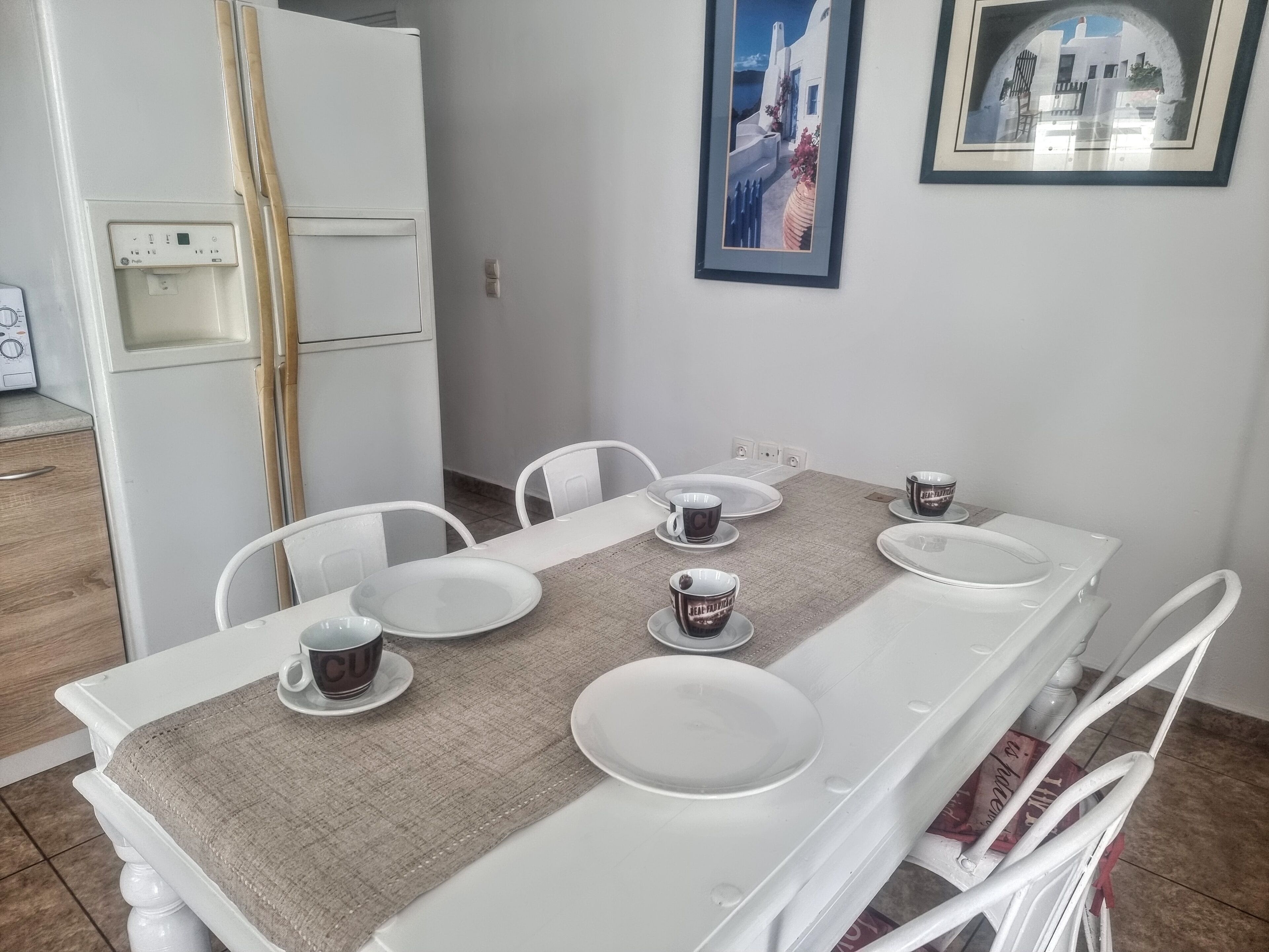 A dining area with a white table set for four, including plates, cups, and a placemat.