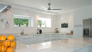 Een moderne keuken met een marmeren aanrechtblad, een inbouwoven, een koelkast en een plafondventilator.