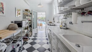 Een moderne keuken met een zwart-wit geruit vloertje, witte kastjes en een grote spoelbak.