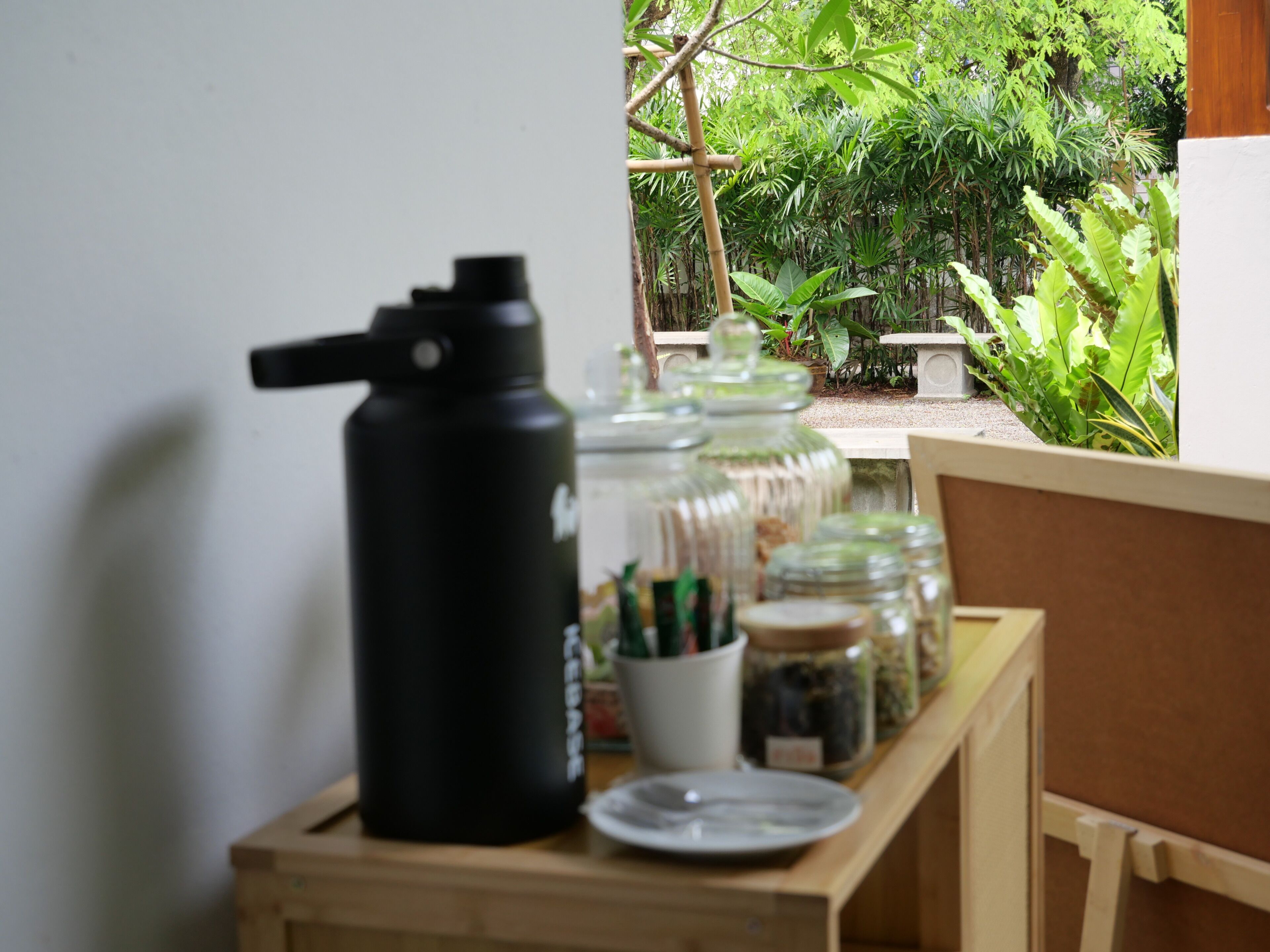 Ein Tisch mit einem schwarzen Thermosbehälter, Glasbehältern mit Etiketten und einer weißen Tasse.