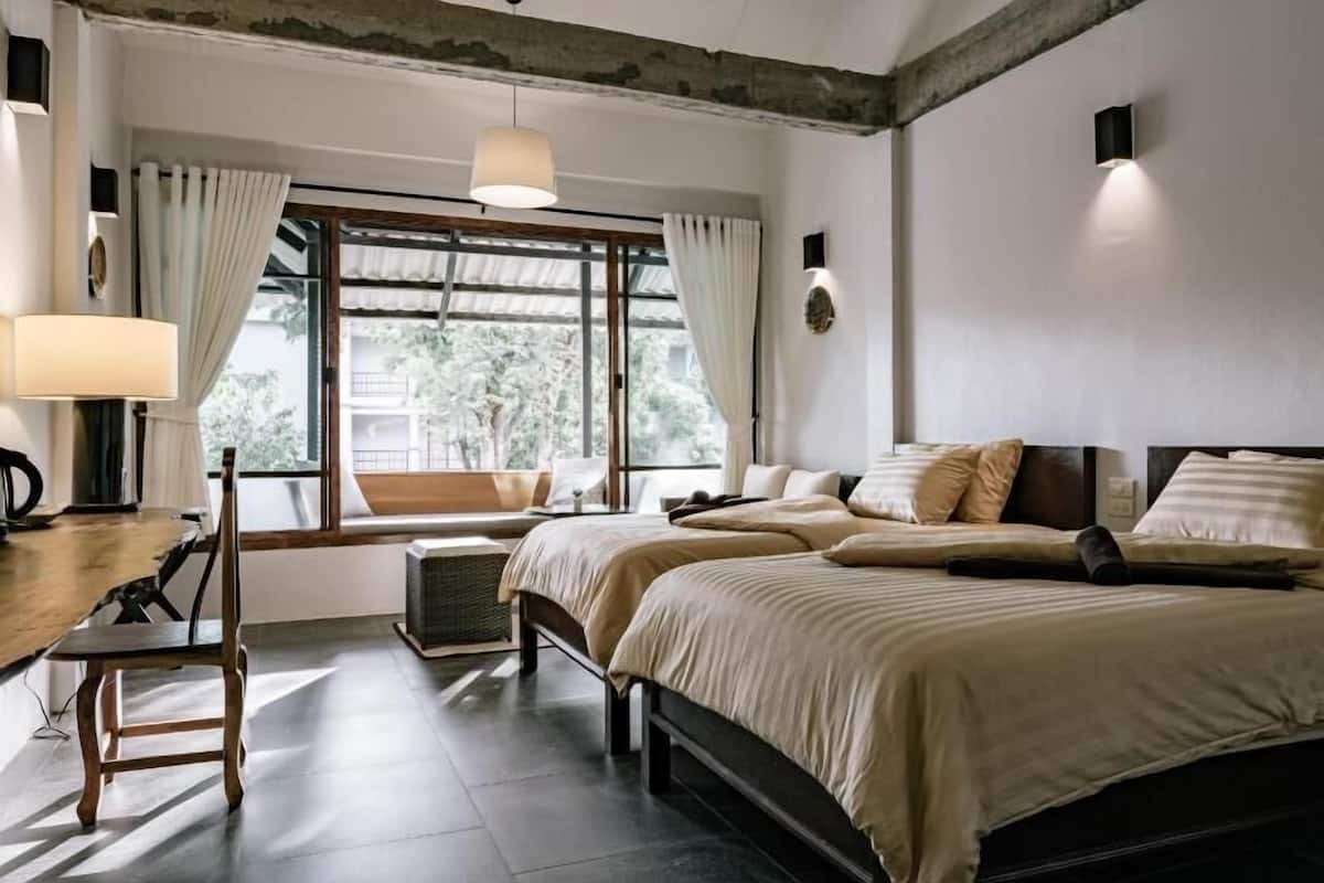 A bedroom with a bed, a desk, a chair, a window with curtains, a ceiling fan, and a wall-mounted light.