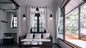 A modern living room with a sofa, a glass coffee table, and a large window with curtains. - Palin Family Cottage (Chiang Rai)