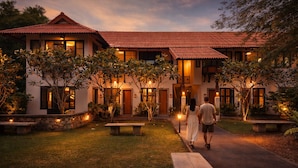 A two-story building with a red-tiled roof, multiple windows, and a well-lit entrance. - Palin Family Cottage (Chiang Rai)
