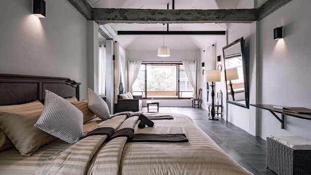 A bedroom with a large bed, a desk, a chair, and a window with curtains. - Palin Family Cottage (Chiang Rai)