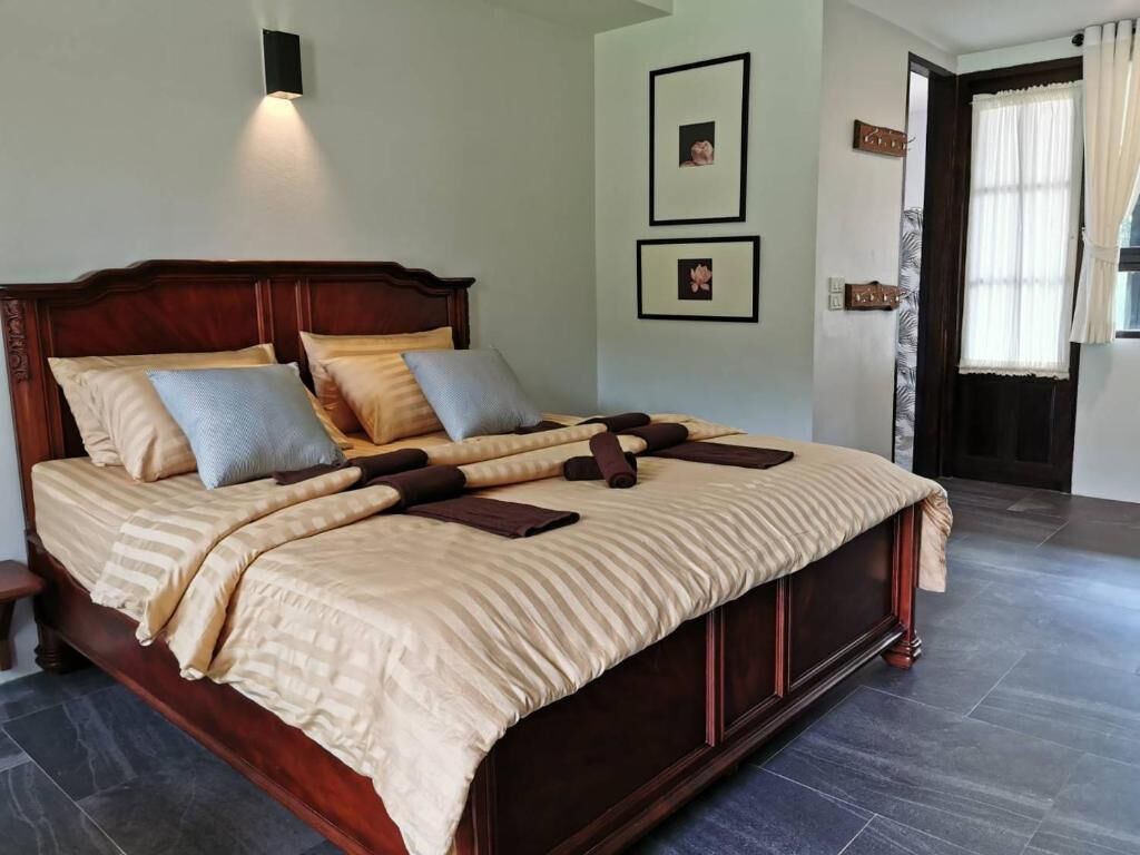 A large bed with a wooden headboard, multiple pillows, and a beige bedspread.