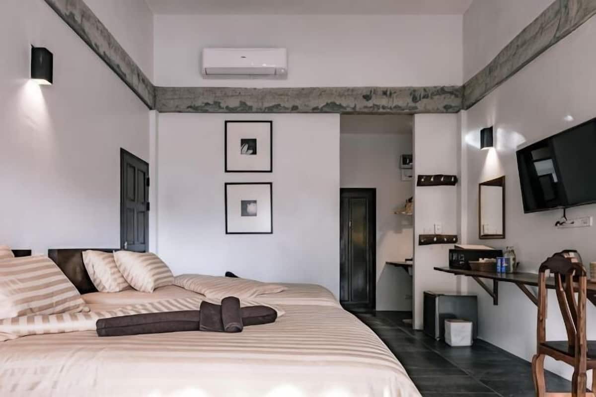 A bedroom with a bed, a chair, a TV, and a small table.