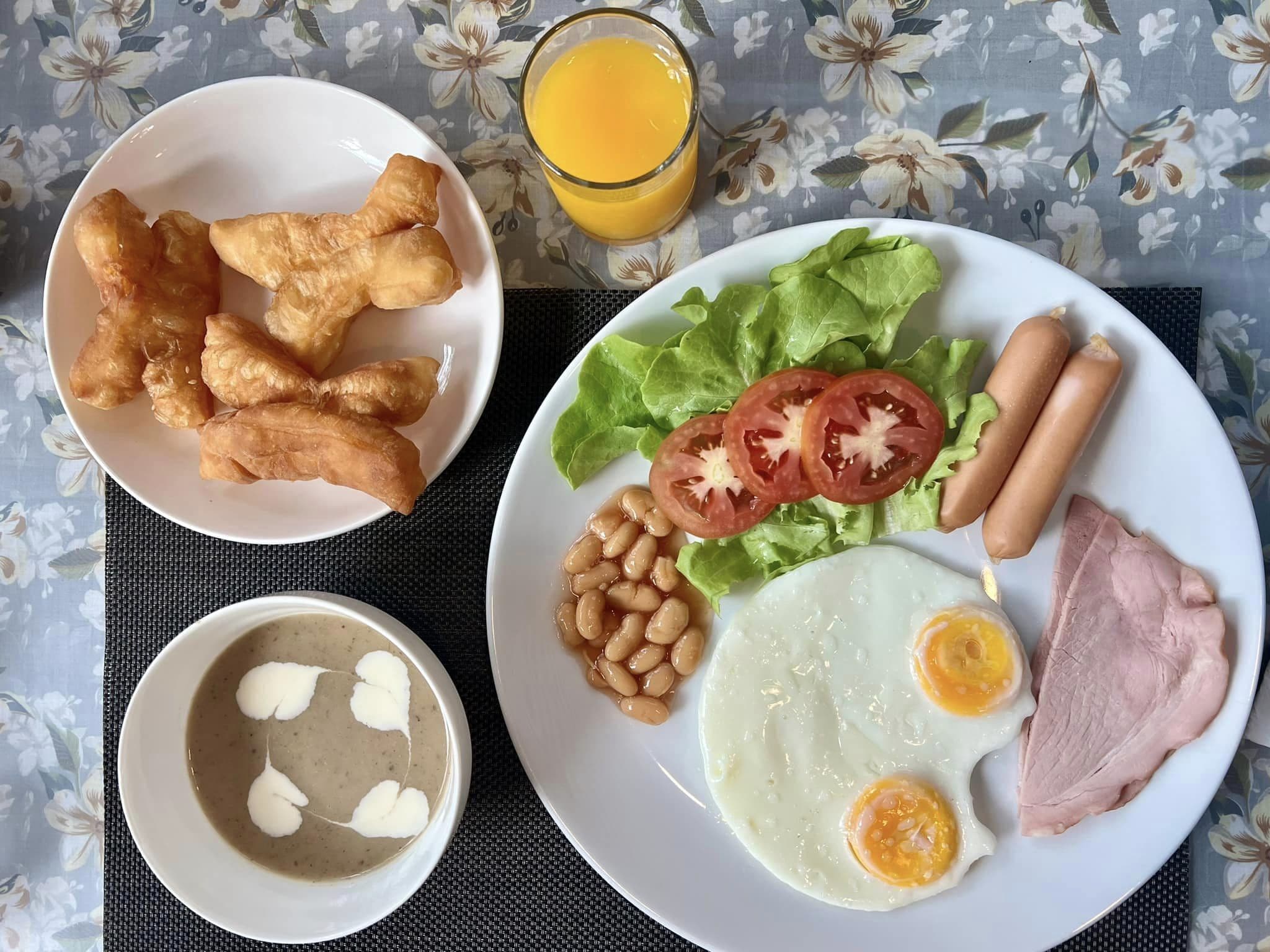 A breakfast plate with eggs, ham, sausages, tomatoes, lettuce, and beans.