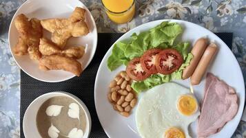 A breakfast plate with eggs, ham, sausages, tomatoes, lettuce, and beans.