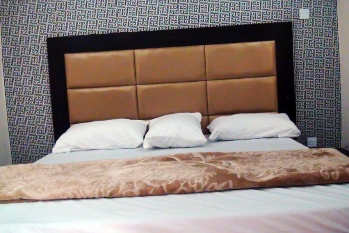 A bed with a headboard, pillows, and a blanket.