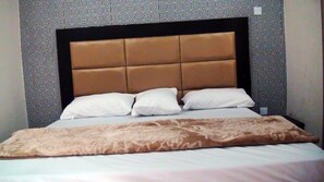 A bed with a headboard, pillows, and a blanket. - Laurel Blue Suites (Port Harcourt)