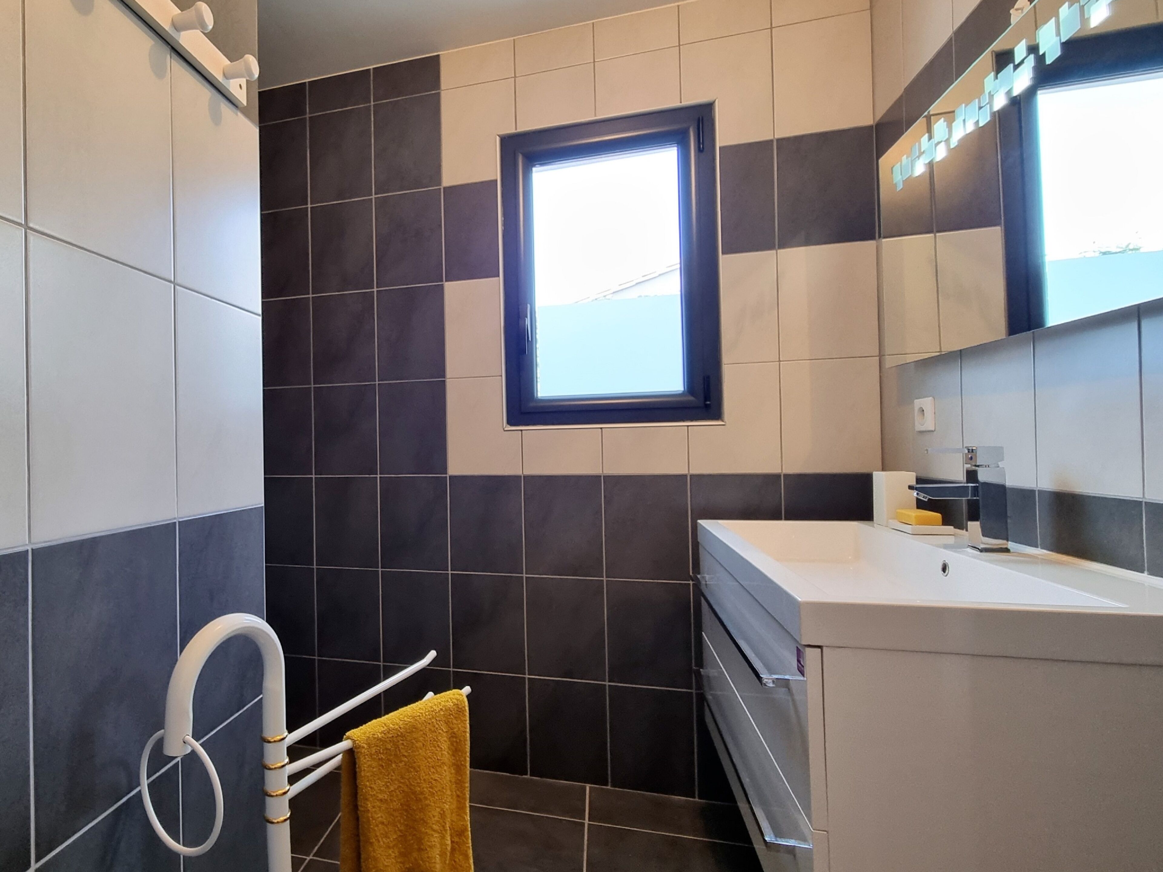 Ein modernes Badezimmer mit Fenster, Handtuchhalter und Waschbecken.