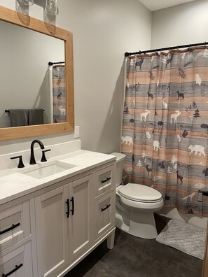 Une salle de bain avec un meuble-lavabo blanc, un miroir, un évier et des toilettes.