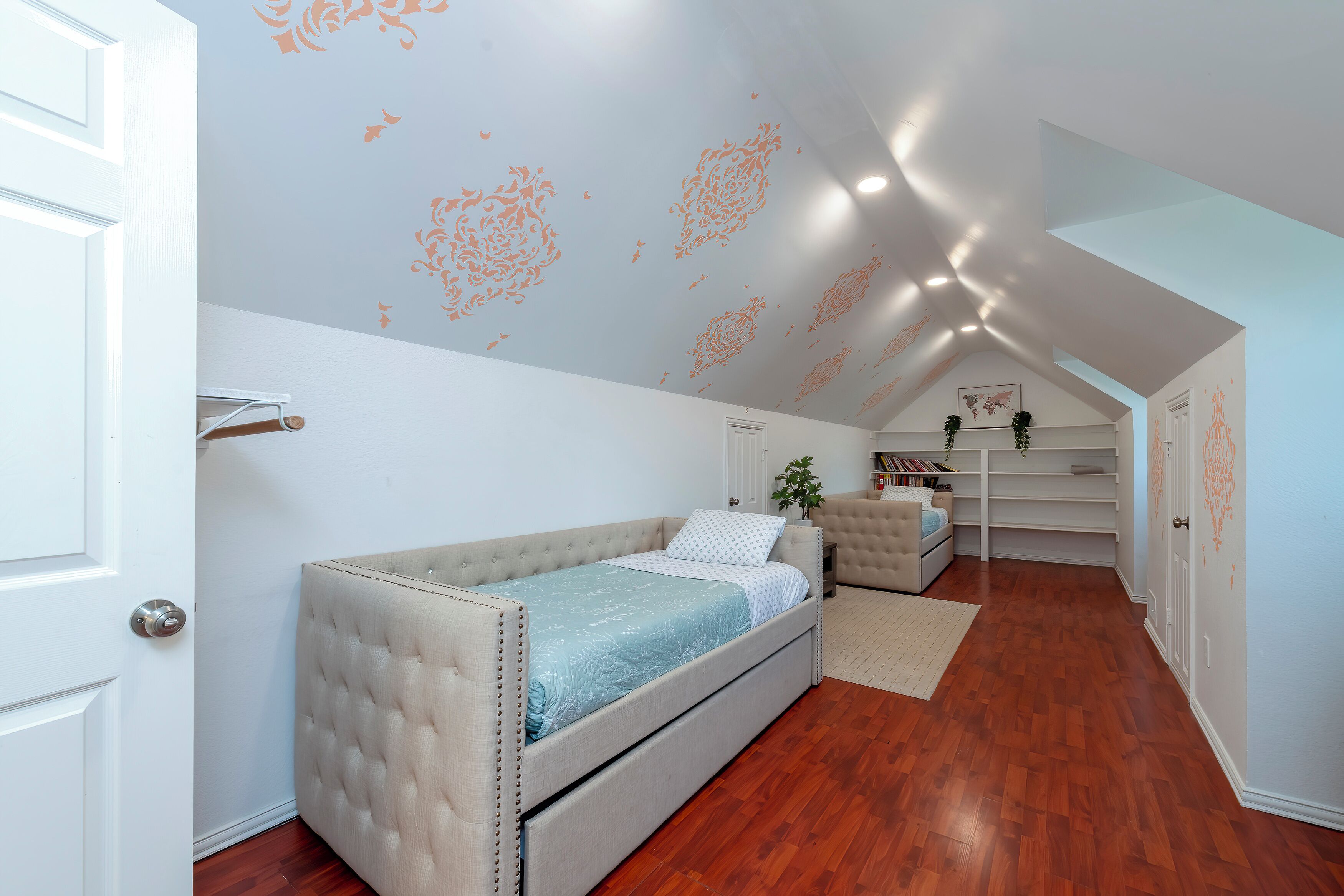 Un dormitorio con cama, una silla, un escritorio y estanterías.