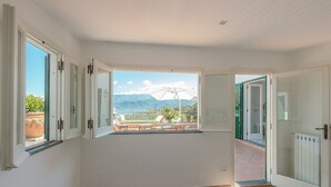 Ein Zimmer mit einem großen Fenster, das einen Blick auf einen Balkon und Berge bietet.