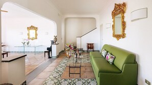 Ein großzügiger Wohnbereich mit einem grünen Sofa, einem Couchtisch und einer Treppe, die zu einer weiteren Ebene führt.