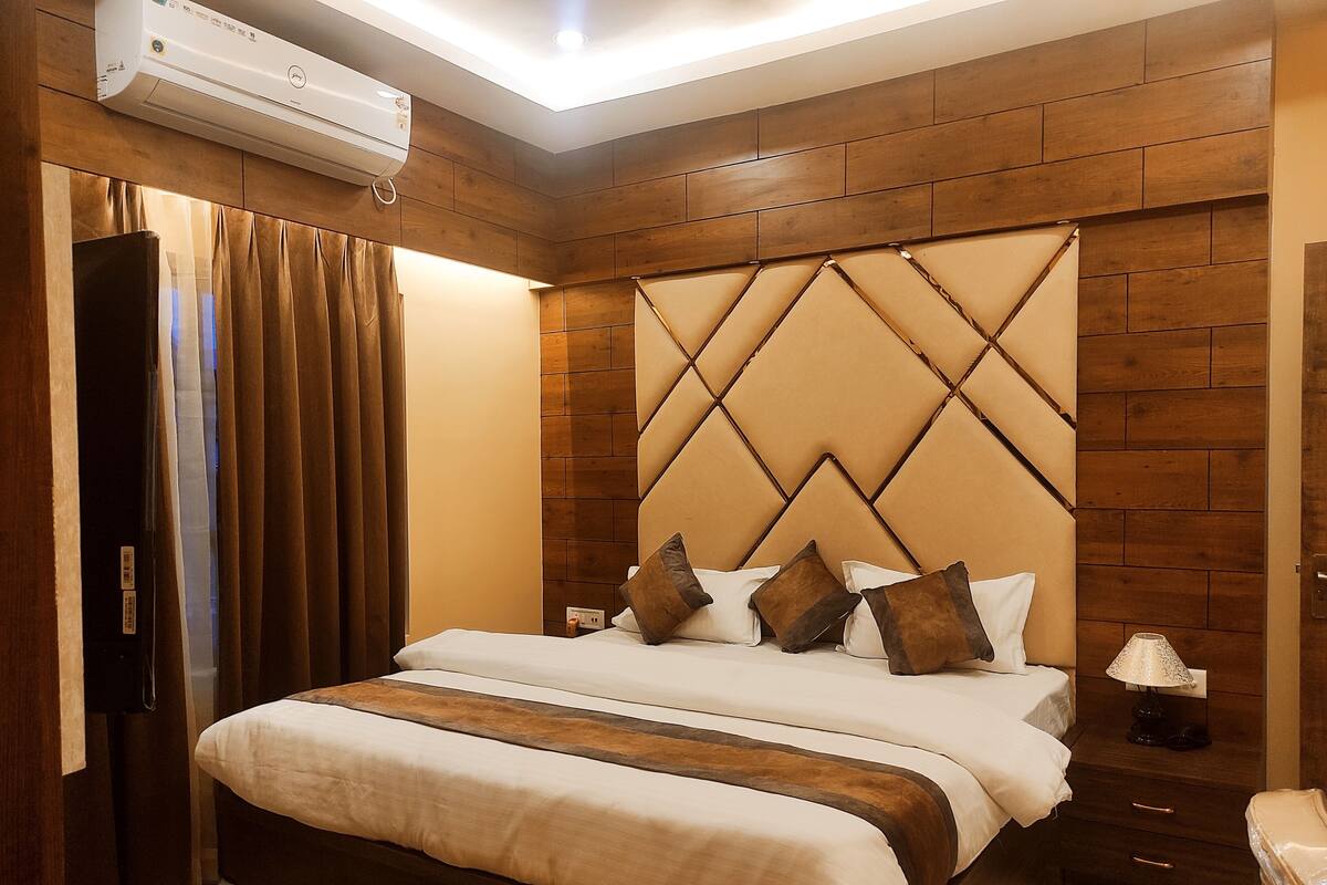 Una habitación de hotel con una cama grande, cabecero de madera y una mesita de noche con lámpara.
