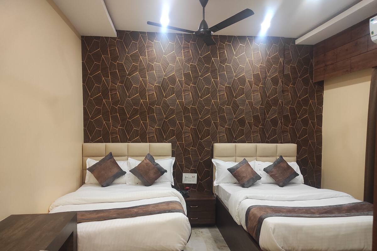Una habitación de hotel con dos camas, un ventilador de techo y una pared con diseño.