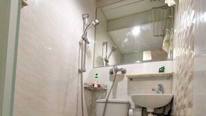 Ein kleines Badezimmer mit Fliesen, einer Toilette, einem Waschbecken und einer Dusche.