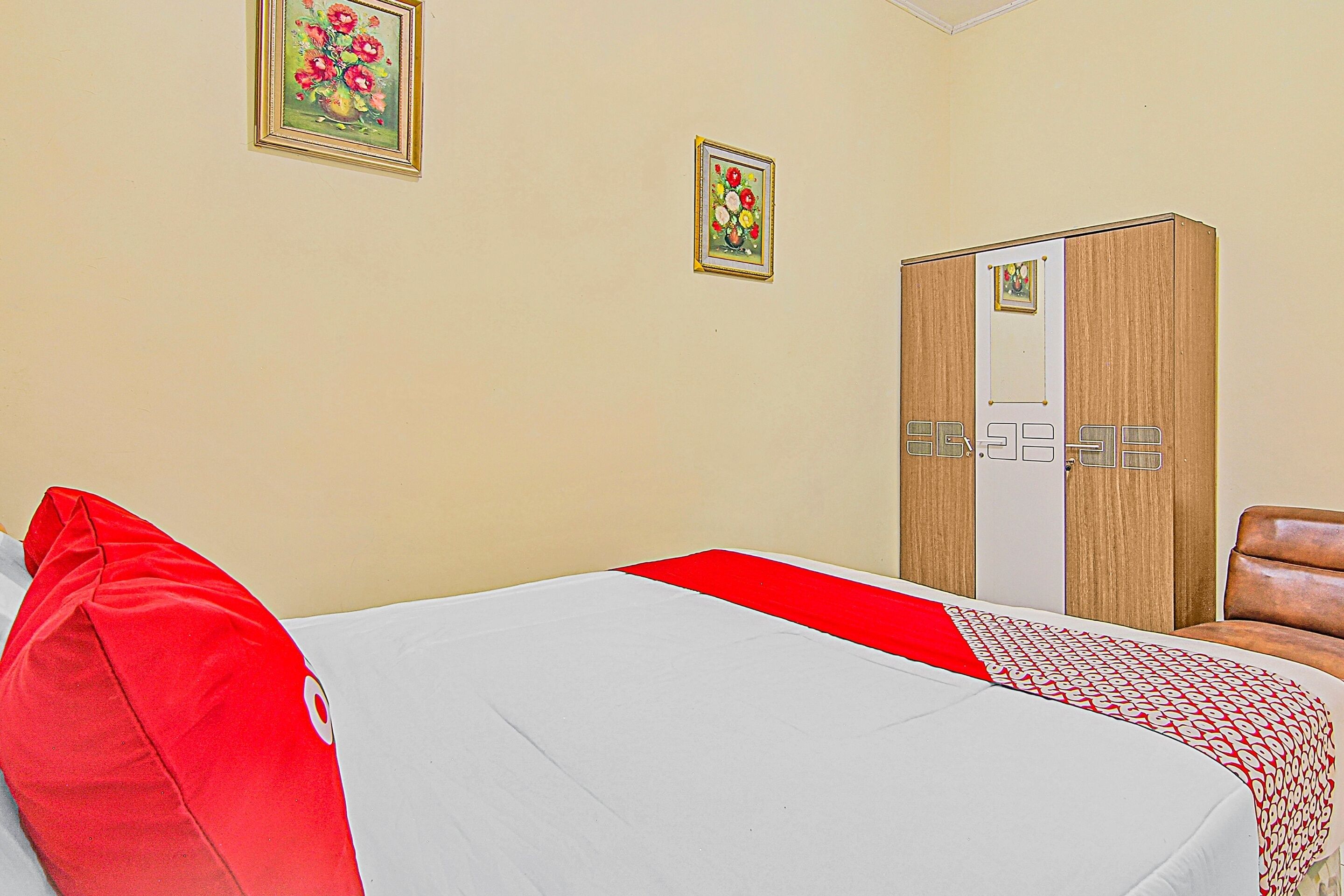 A hotel room with a bed, a wardrobe, and two framed pictures on the wall.