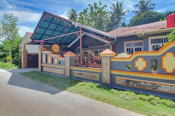 A house with a distinctive architectural style, featuring a covered porch, a gated entrance, and a decorative wall with geometric patterns.