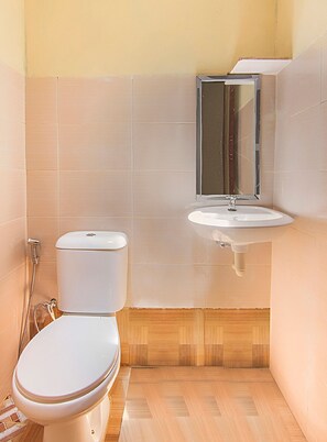 A small bathroom with a toilet, a sink, and a mirror.