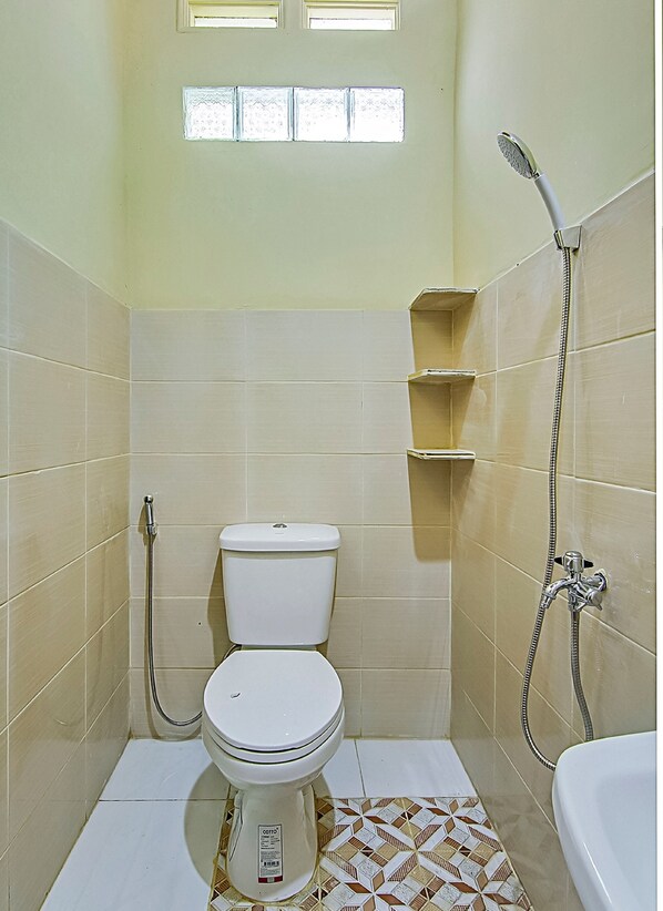 A small, tiled bathroom with a toilet, a shower, and a sink.