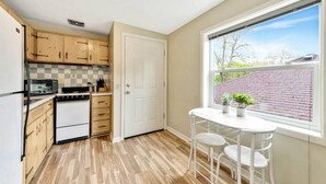 A kitchen with wooden cabinets, a white stove, a microwave, and a dining table with chairs.