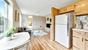 A modern kitchen with wooden cabinets, a white refrigerator, and a dining area with a round table and chairs.