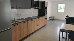 Una cocina moderna con armarios de madera, un refrigerador de acero inoxidable y un horno empotrado.