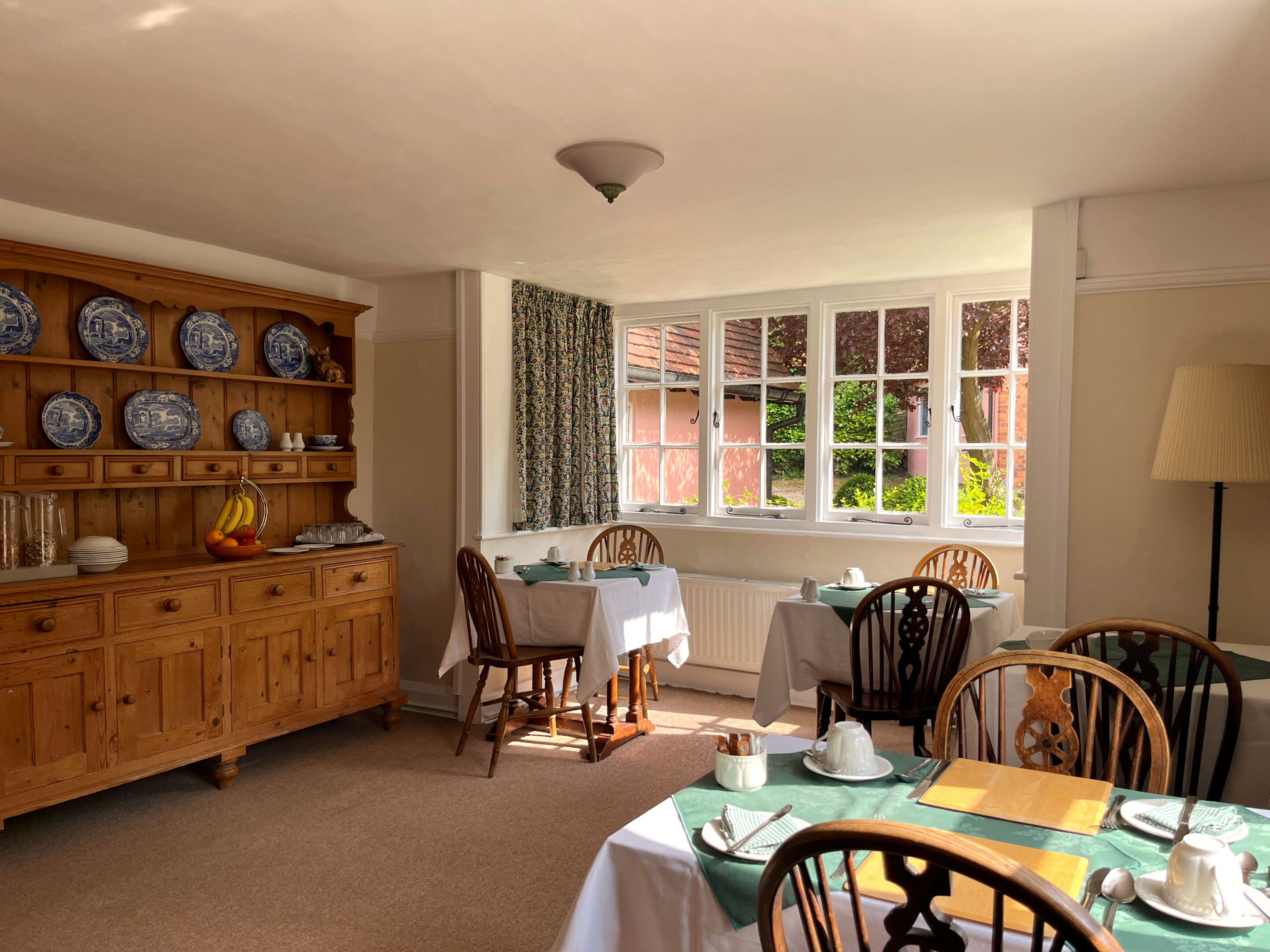 A dining area with wooden cabinets, a table set for four, and a window with curtains.