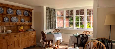 A dining area with wooden cabinets, a table set for four, and a window with curtains.