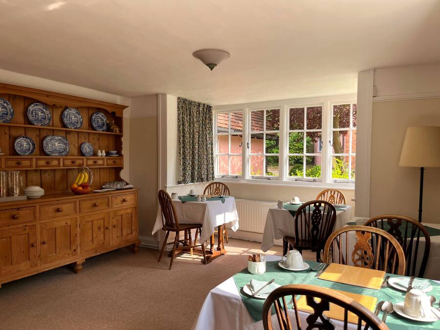 A dining area with wooden cabinets, a table set for four, and a window with curtains.