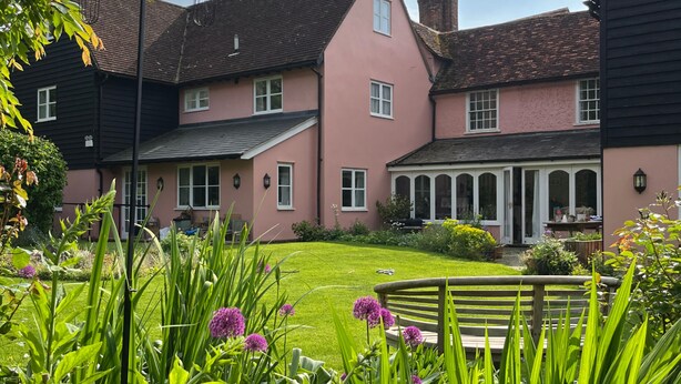 A large pink building with a well-maintained lawn and garden in front. - The Cottage Guest House (Bishop's Stortford)