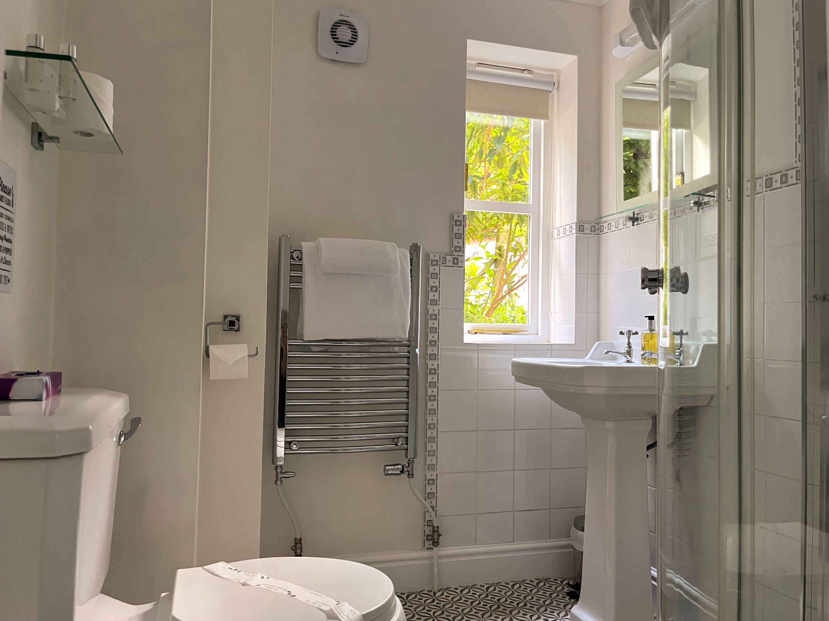 Ein Badezimmer mit Toilette, Handtuchhalter, Fenster und Waschbecken.