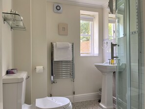 Een badkamer met toilet, een douchecabine van glas, een wastafel en een handdoekhouder.